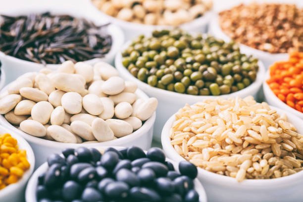 Various raw legumes and rice in white bowls